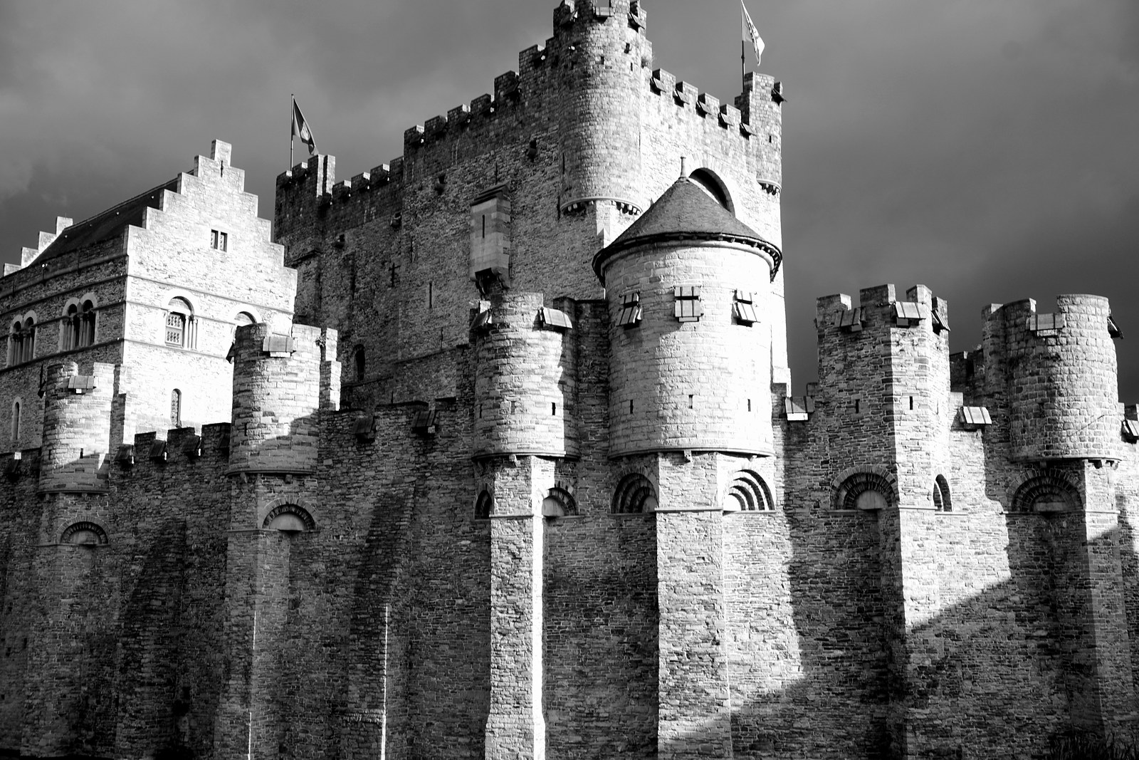 Schwarzweißfotografie einer stark beleuchteten Genter Burgmauer unter dunklem Himmel