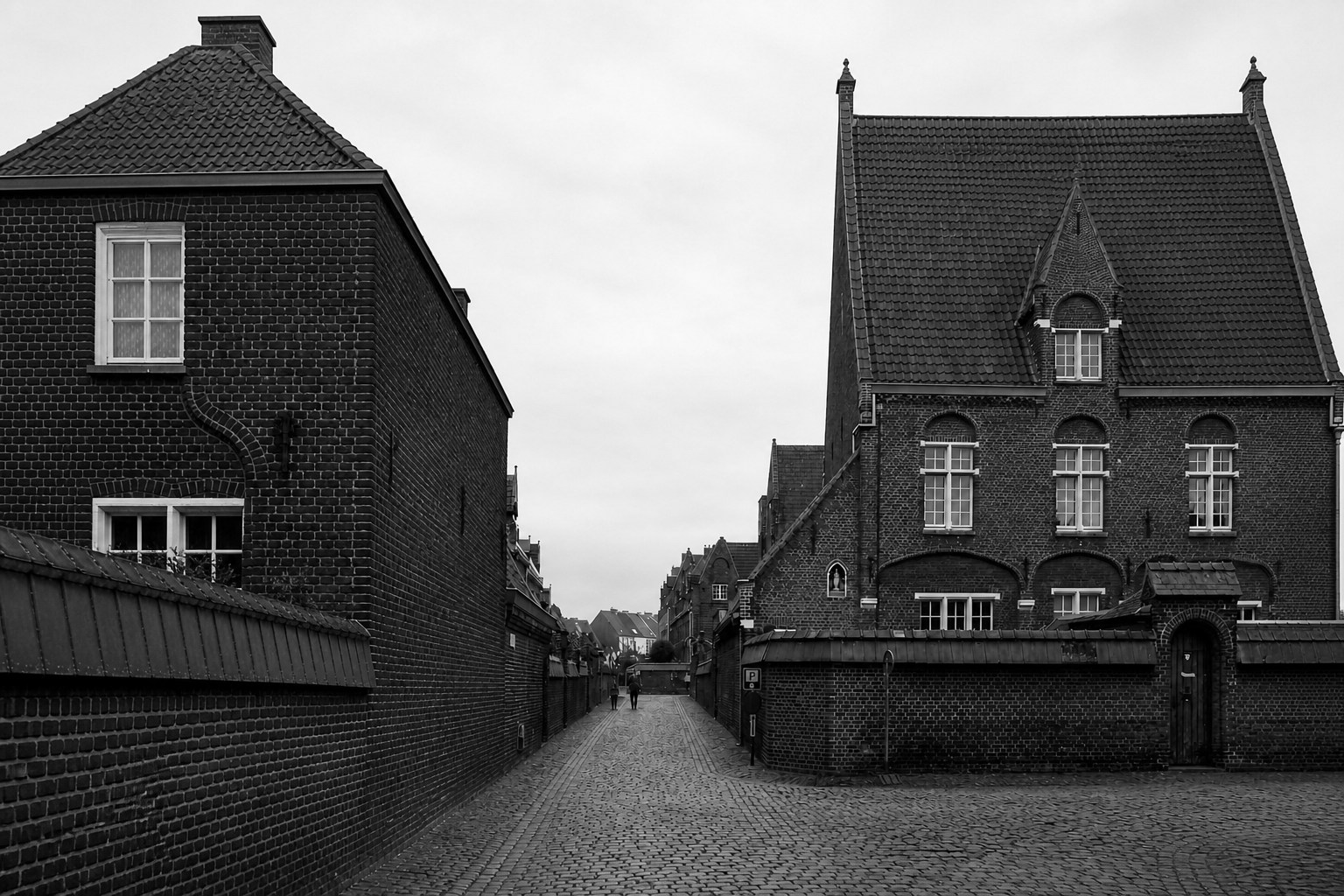 Schwarzweißfotografie eines ruhigen Genter Backsteinensembles mit gepflasterter Straße