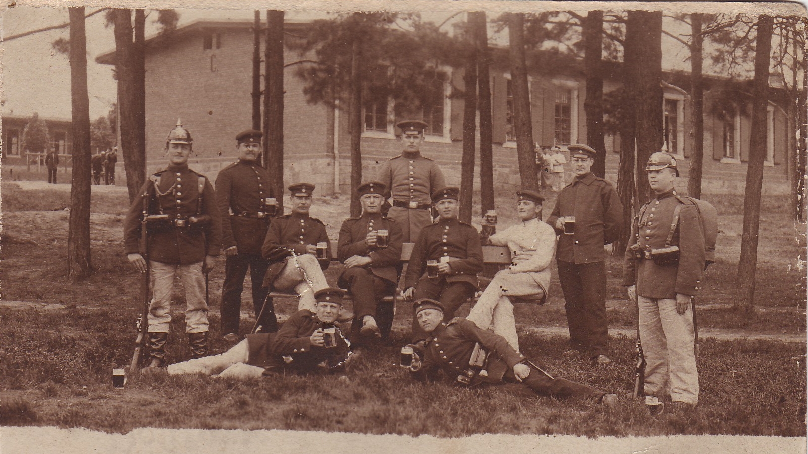 Historisches Gruppenfoto mehrerer Männer in Uniform und Zivilkleidung vor einem Gebäude